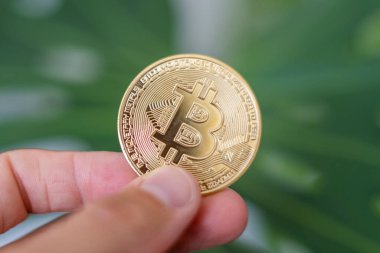 Bitcoin. Elinde BTC sembolü olan altın sikke. Kripto para birimi konsepti gibi sanal varlıklara yatırım yapan kişi