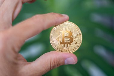 Bitcoin. Elinde BTC sembolü olan altın sikke. Kripto para birimi konsepti gibi sanal varlıklara yatırım yapan kişi
