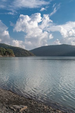 Akşam bulutları, yeşil tepelerle çevrili Abrau gölünün sakin sularına yansıyor..