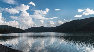 Akşam bulutları, yeşil tepelerle çevrili Abrau gölünün sakin sularına yansıyor..