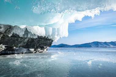 Baykal Gölü 'ndeki kayalık bir ada uzun buz sarkıtları ile çevrilidir ve şeffaf buzlarla çevrilidir..