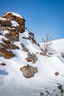 Sarı bir kaya, kar beyazı Tazheran bozkırının ortasında, tepenin zirvesini taçlandırır..