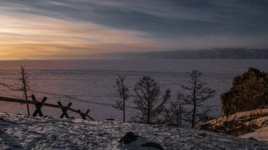 Batan güneşin son ışınları Khuzhir Körfezi 'ndeki Baykal Gölü' nün buzunu aydınlatıyor..