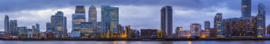 Detailed, high resolution panoramic photo about the skyscrapers of Canary Wharf at blue hour - London, UK clipart