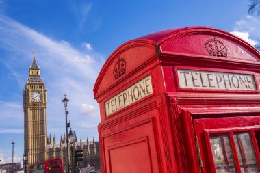 Iconic Red British telephone box with Big Ben on a sunny afternoon clipart