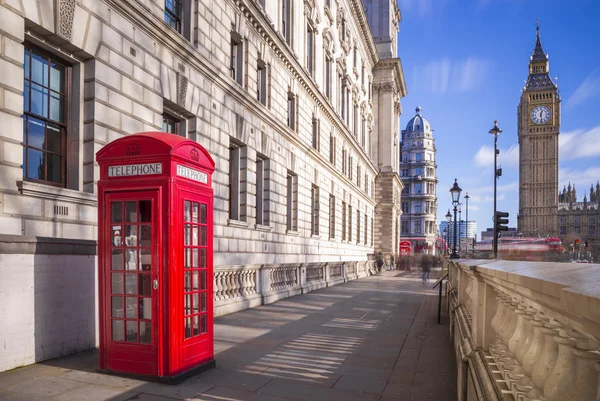 La tradicional cabina telefónica británica roja con Big Ben y el autobús Double Decker al fondo en una tarde soleada con cielo azul y nubes - Londres, Reino Unido —  Fotos de Stock