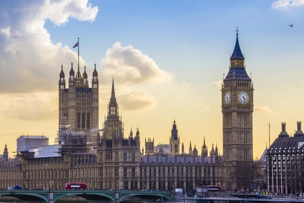 Λονδίνο, Αγγλία - το περίφημο Μπιγκ Μπεν και τα κτίρια του Κοινοβουλίου με τη γέφυρα Westminster και το διώροφο κόκκινο λεωφορείο στο ηλιοβασίλεμα — Φωτογραφία Αρχείου