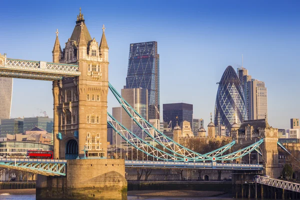 Londra, İngiltere - sabah güneş ışığı kırmızı Çift katlı otobüs ile ikonik Tower Bridge ve arka plan banka bölge — Stok fotoğraf