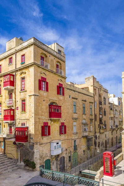 Malta, Valletta - Streetview med traditionella röda balkonger och fönster och röd telefonkiosk — Stockfoto