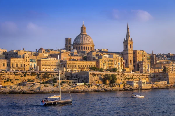 Valletta, Malta - segelbåtar och den berömda St.Paul 's Cathedral med den antika staden Valletta vid solnedgången — Stockfoto