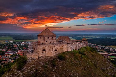 Sumeg, Macaristan - Veszprem ilçesindeki ünlü Sumeg Yüksek Şatosu 'nun günbatımında fırtına bulutları ve bir yaz öğleden sonra arka planda dramatik günbatımı renkleriyle hava panoramik görüntüsü