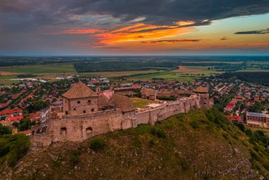 Sumeg, Macaristan - Veszprem ilçesindeki ünlü Sumeg Yüksek Şatosu 'nun günbatımında fırtına bulutları ve bir yaz öğleden sonra arka planda dramatik günbatımı renkleriyle hava panoramik görüntüsü