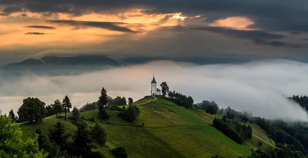 Jamnik Slovenia 在Jamnik Primoz山顶教堂的神奇雾蒙蒙的夏日早晨 日出的时候雾气轻轻吹散在小教堂后面 背景是金色的天空和朱利安阿尔卑斯山 — 图库照片