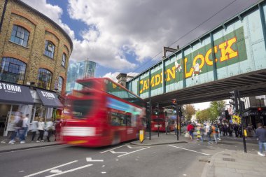 LONDON, UNITED KINGDOM - SEPTEMBER 26, 2015: Camden Lock Bridge and Stables Market, famous alternative culture shops in Camden Town, London, England. Double decker bus goes under the bridge. clipart
