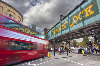 LONDON - October 1. 2015: Double Decker bus goes under Camden Lock Bridge at Camden Stables Market, famous alternative culture shops on in Camden Town, London, United Kingdom clipart
