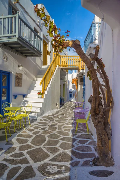 Streetview of Mykonos town with yellow chairs and tables and stairs, Greece — Stock Photo, Image