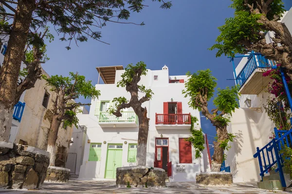 Pequeña plaza de en Mykonos ciudad con cielo azul claro y árboles, Grecia — Foto de Stock