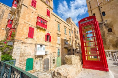 Old street of Valletta with red phone booth and traditional balconies and blue sky - Malta clipart