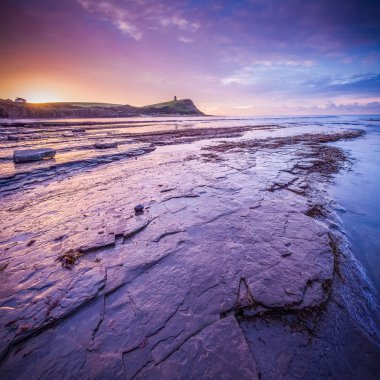 Kimmeridge Bay, Dorset, İngiltere'de kayalar ve düşük gelgit ile güzel renkli gündoğumu
