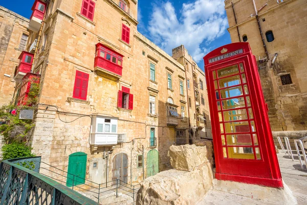 Kırmızı telefon kulübesi ve geleneksel Balkonlu ve mavi gökyüzü - Malta Valletta eski sokak — Stok fotoğraf