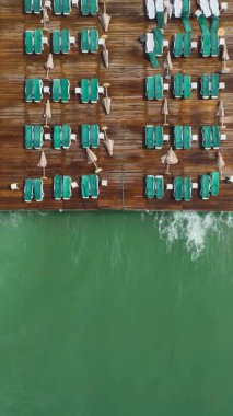 Şemsiyeli iskele ve yumuşak turkuaz su hareketi.