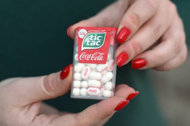 KHARKOV, UKRAINE - 16 Ekim 2020: Genç kız koka-kola tadında naneli şeker paketi tutuyor. Tic Tac, Ferrero tarafından üretilen bir nane şekeri markasıdır.