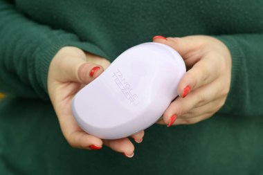 KHARKOV, UKRAINE - 16 Ekim 2020: Genç kız Tangle Teezer pembe saç fırçasını tutuyor. Tangle Teezer, saç fırçalarını çözen İngiliz bir üretici.