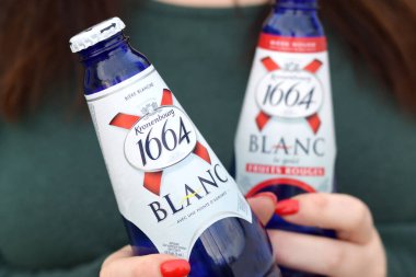 KHARKOV, UKRAINE - 16 Ekim 2020: Genç kız 1664 Kronenbourg Blanc bira bardağını açık havada tutuyor. 1664 Blanc, Fransız bira fabrikası Kronenbourg 'dan dünya çapında ihraç edilen buğday birasıdır.