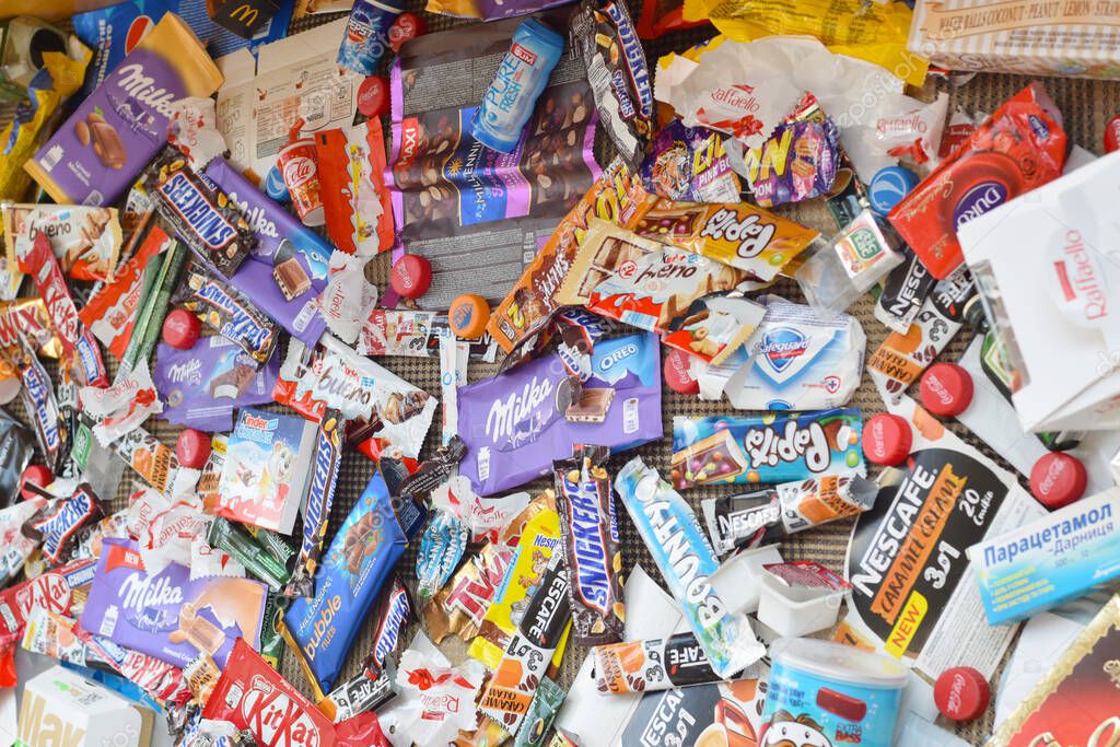 KHARKOV, UKRAINE - APRIL 8, 2020: Many wrappings and cans from used products by famous worldwide brands. Pattern of trash of various colors and materials