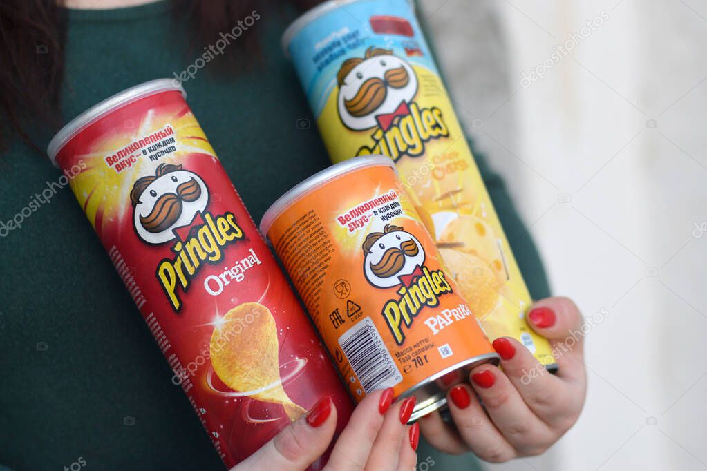 KHARKOV, UKRAINE - OCTOBER 16 2020: Young girl holds few pringles potato chips cylinder packs. Pringles is a brand of potato snack chips owned by the Kellogg Company