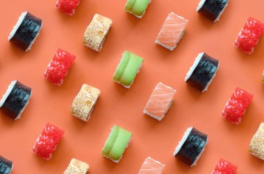 Turuncu arka planda farklı Asya suşi çeşitleri var. Minimalizm üst görünüm düz Japon yemekleri ile yatıyordu