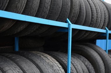 Otomobil mağazasında çeşitli araba lastikleriyle dolu raflar. Bir sürü siyah lastik. Lastik yığını arka planı. Seçici odak