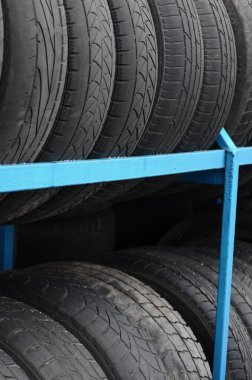 Otomobil mağazasında çeşitli araba lastikleriyle dolu raflar. Bir sürü siyah lastik. Lastik yığını arka planı. Seçici odak