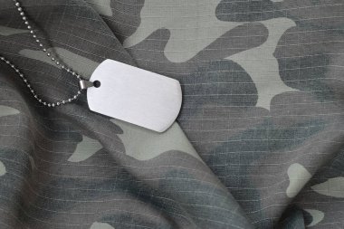 Kamuflaj üniformasında künyesi olan gümüşi askeri boncuklar. Ordu jetonu asker kamuflaj ceketinin arka tarafında.