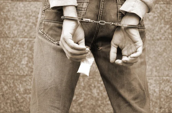 Aresztowany Handlarz Narkotyków Kajdankach Małym Pakietem Heroiny Tle Ciemnej Ściany — Zdjęcie stockowe