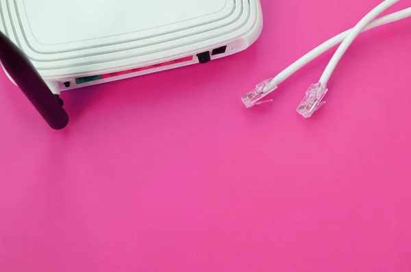 Internet router and Internet cable plugs lie on a bright pink background. Items required for Internet connection