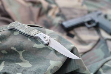 Taktik bıçak ve tabanca kamuflaj yeşil kumaşın üzerinde. Özel operasyon ögeleri ya da kendini savunma kiti