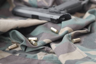9mm 'lik mermiler ve tabancalar katlanmış yeşil kumaşın üzerinde duruyor. Atış menzili ya da savunma kiti. Altın kovanlar tabancanın yanında.