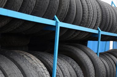 Otomobil mağazasında çeşitli araba lastikleriyle dolu raflar. Bir sürü siyah lastik. Lastik yığını arka planı. Seçici odak