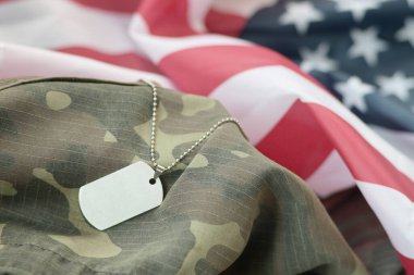 Birleşik Devletler kumaş bayrağı ve kamuflaj üniformasında künyesi olan gümüş askeri boncuklar. Amerikan bayrağında askeri jeton. Yakın plan. Anma Günü konsepti