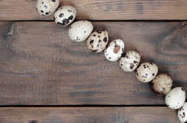 Koyu kahverengi ahşap yüzeyde bıldırcın yumurtaları, üst görüş, metin için boş yer, tarif