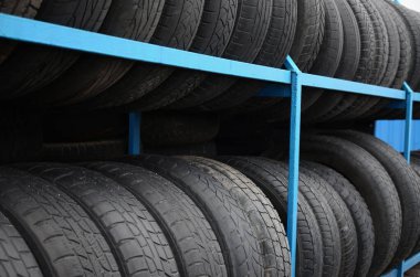 Otomobil mağazasında çeşitli araba lastikleriyle dolu raflar. Bir sürü siyah lastik. Lastik yığını arka planı. Seçici odak