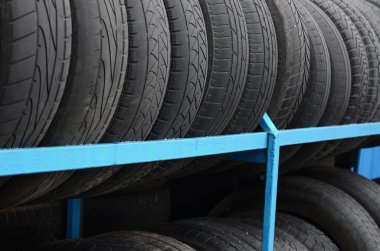 Otomobil mağazasında çeşitli araba lastikleriyle dolu raflar. Bir sürü siyah lastik. Lastik yığını arka planı. Seçici odak
