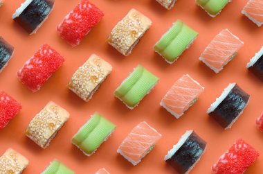 Turuncu arka planda farklı Asya suşi çeşitleri var. Minimalizm üst görünüm düz Japon yemekleri ile yatıyordu