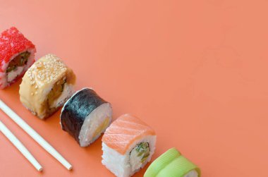 Turuncu arka planda farklı Asya suşi çeşitleri var. Minimalizm üst görünümü düz Japon yemekleri ile yatıyordu