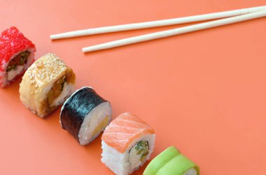 Turuncu arka planda farklı Asya suşi çeşitleri var. Minimalizm üst görünümü düz Japon yemekleri ile yatıyordu