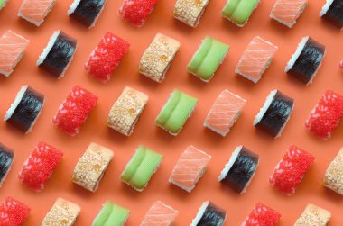 Turuncu arka planda farklı Asya suşi çeşitleri var. Minimalizm üst görünüm düz Japon yemekleri ile yatıyordu