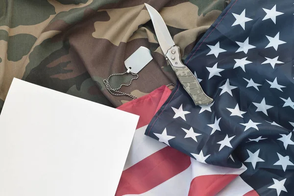 ブランクペーパーには 迷彩服とアメリカ国旗のナイフと軍犬のタグネックレスがあります ノートや米国退役軍人の日への感謝のためのスペース — ストック写真