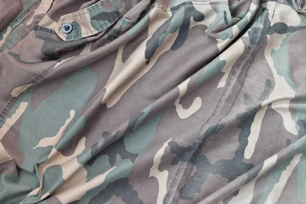 Camouflage background texture as backdrop for military service design projects. Back side of conscripts camouflage jacket with many pleats on crumpled fabric