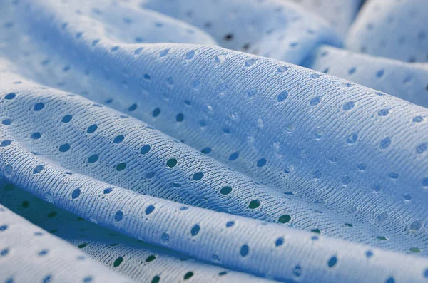 Blue mesh sport wear fabric textile pattern background. Blue color football jersey clothing fabric texture sports wear. Breathable porous poriferous material air ventilation with small holes